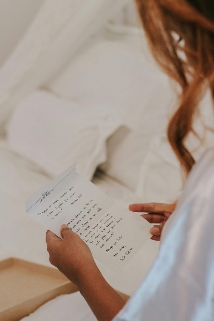 Une photo d'une femme assise en tenant et lisant une lettre manuscrite.